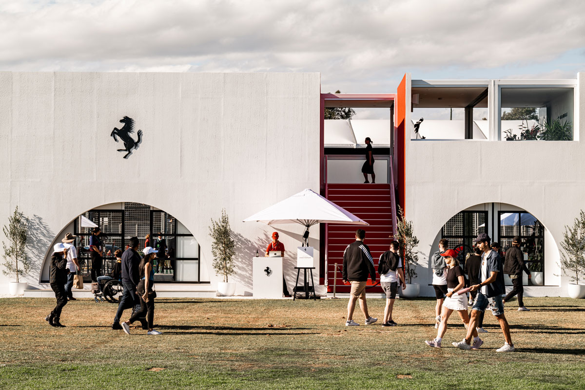 A photograph of an outdoor event featuring a man standing at a podium with a Ferrari logo on it